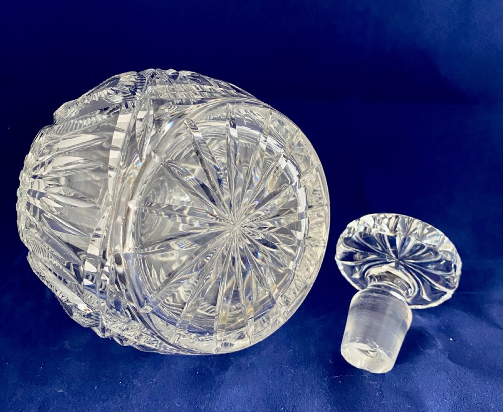 A clear cut crystal decanter featuring a spherical body with geometric diamond facets, three neck rings, and a matching rounded stopper. View III