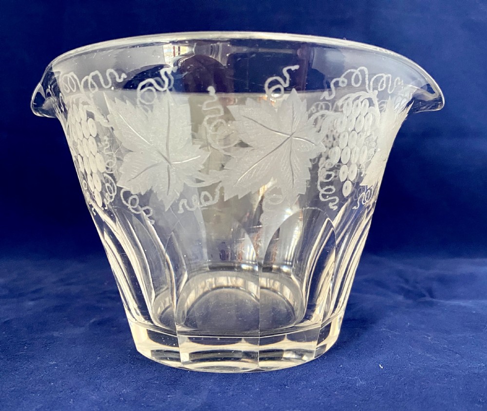 A clear Victorian glass wine rinser featuring acid-etched grapevine decoration around the top edge, dual lip spouts, and a panel-cut lower body.