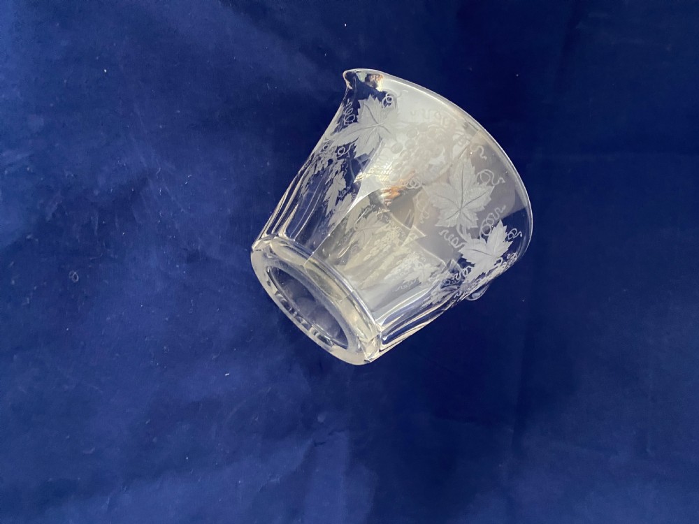 A clear Victorian glass wine rinser featuring acid-etched grapevine decoration around the top edge, dual lip spouts, and a panel-cut lower body. View VI