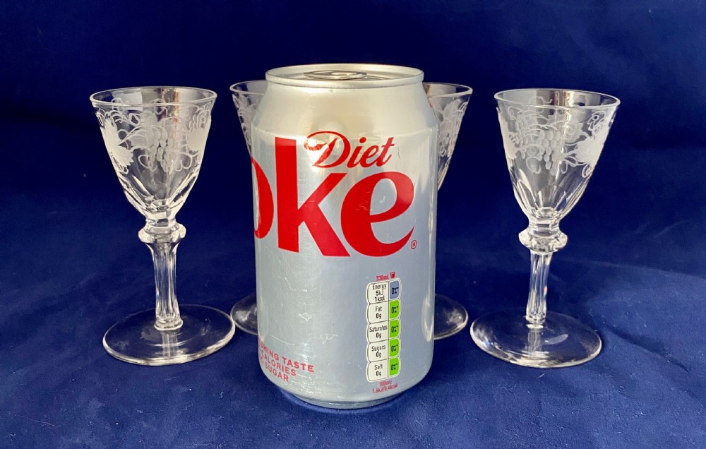 A set of four clear Victorian glass cordial glasses featuring acid-etched grape and vine motifs around the bowls and faceted stems. View VII