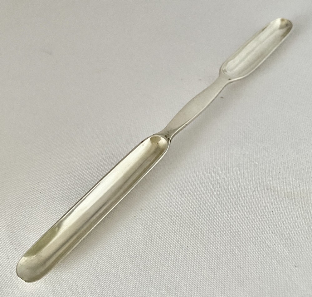 A Victorian double-ended sterling silver marrow scoop with polished elongated bowls resting on a plain background.