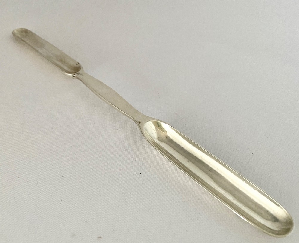A Victorian double-ended sterling silver marrow scoop with polished elongated bowls resting on a plain background. View II