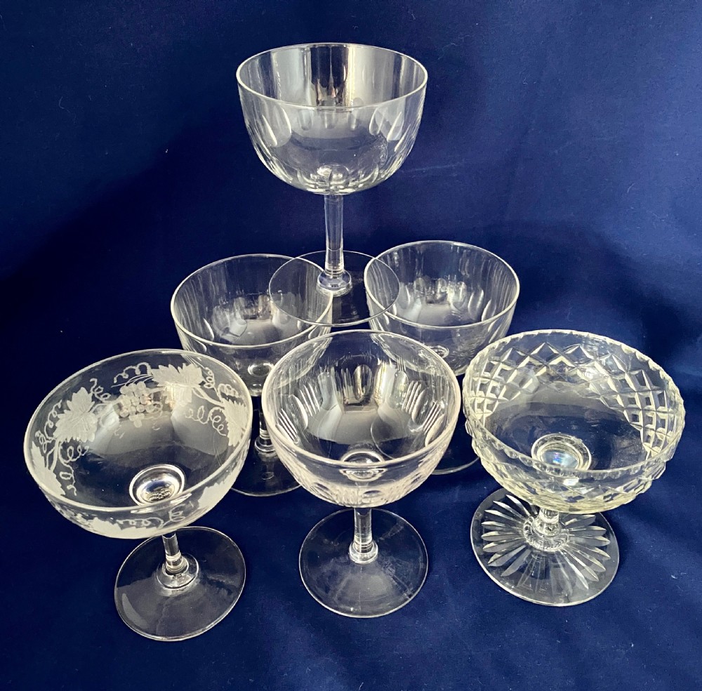 A set of six clear Edwardian stemware champagne coupes with assorted hand-cut and etched decorative patterns.