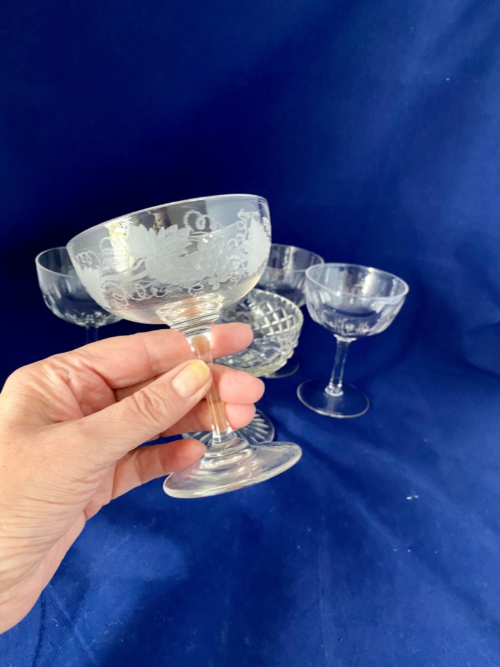 A set of six clear Edwardian stemware champagne coupes with assorted hand-cut and etched decorative patterns. View IV
