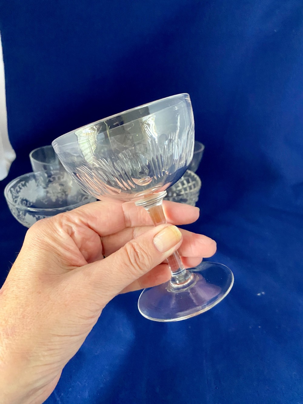A set of six clear Edwardian stemware champagne coupes with assorted hand-cut and etched decorative patterns. View V