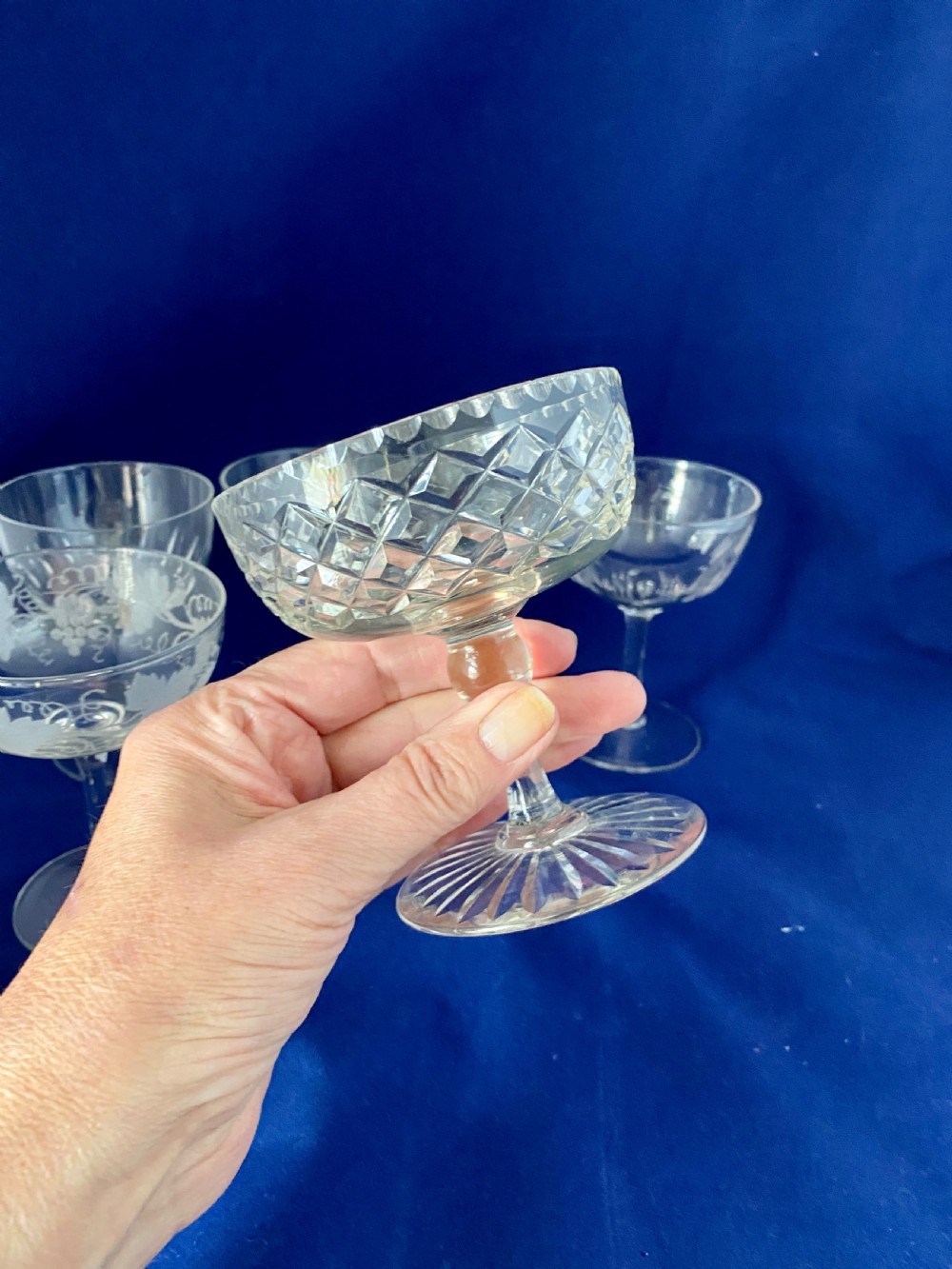 A set of six clear Edwardian stemware champagne coupes with assorted hand-cut and etched decorative patterns. View VI