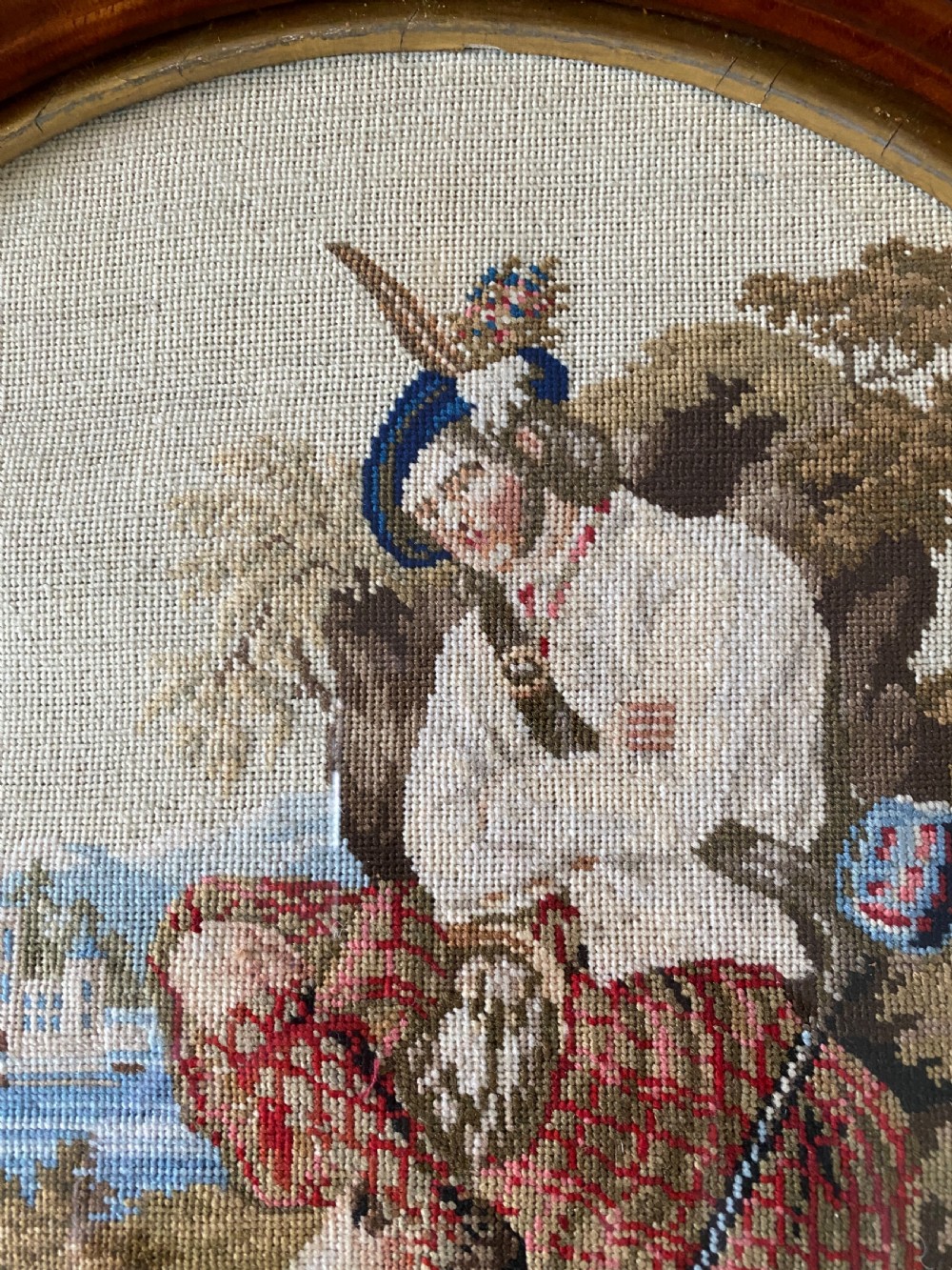A circular Victorian woolwork picture depicting a seated Scottish Highlander in a kilt, housed in a pierced carved wooden frame. View VII