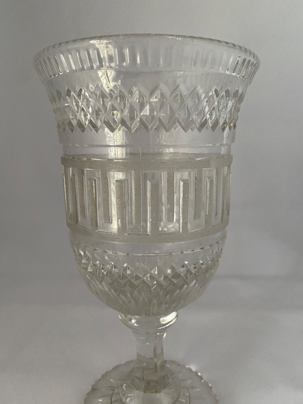 A clear glass Victorian celery vase featuring flared rim, diamond cut bands, a Greek key motif, and a scalloped circular pedestal foot. View II