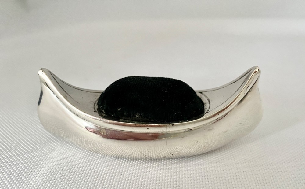 An Edwardian sterling silver pin cushion crafted in the shape of a canoe with a dark velvet insert and visible hallmarks on the exterior side. View IV