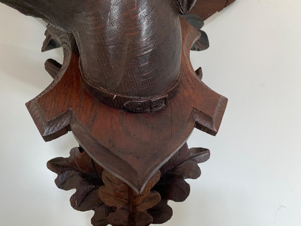 A Victorian carved oak corner bracket featuring a high-relief carved dog head surrounded by oak leaves and acorns beneath a curved corner shelf. View III