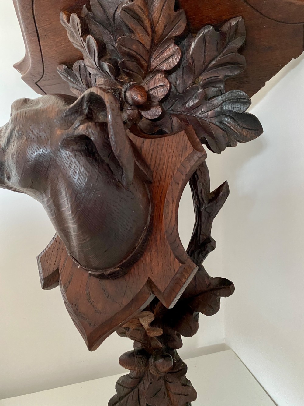 A Victorian carved oak corner bracket featuring a high-relief carved dog head surrounded by oak leaves and acorns beneath a curved corner shelf. View VI