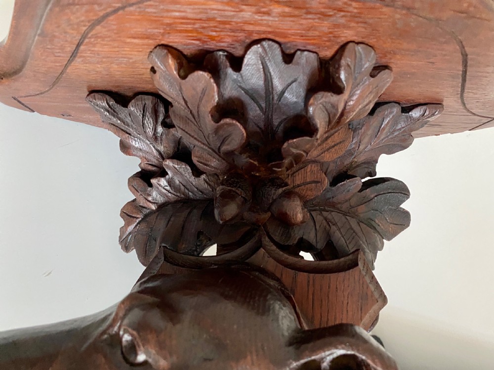 A Victorian carved oak corner bracket featuring a high-relief carved dog head surrounded by oak leaves and acorns beneath a curved corner shelf. View IX