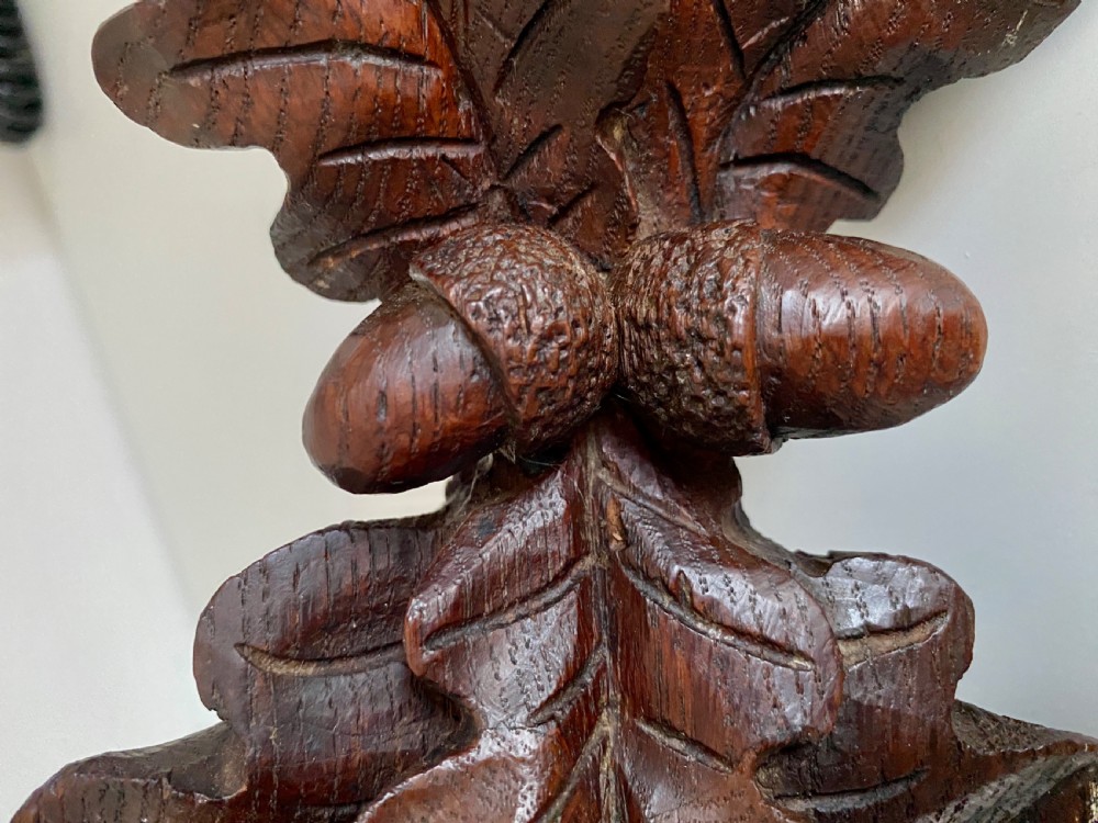 A Victorian carved oak corner bracket featuring a high-relief carved dog head surrounded by oak leaves and acorns beneath a curved corner shelf. View X