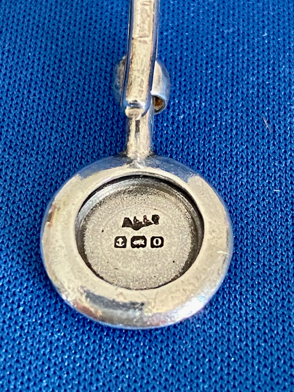 An Edwardian sterling silver napkin clip featuring a curved hook attached to a round engraved medallion. View III