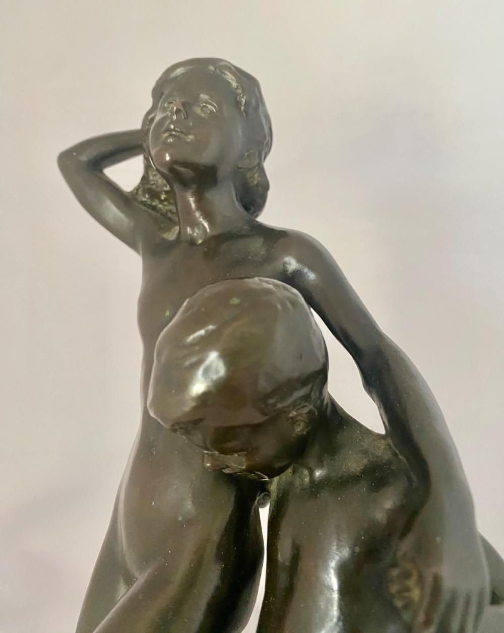 A dark patinated bronze figural group depicting two children in dynamic motion standing atop a moulded circular base. View II