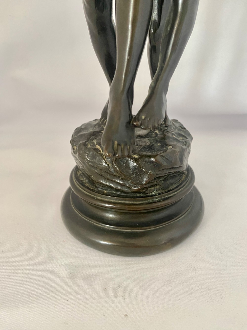 A dark patinated bronze figural group depicting two children in dynamic motion standing atop a moulded circular base. View VII