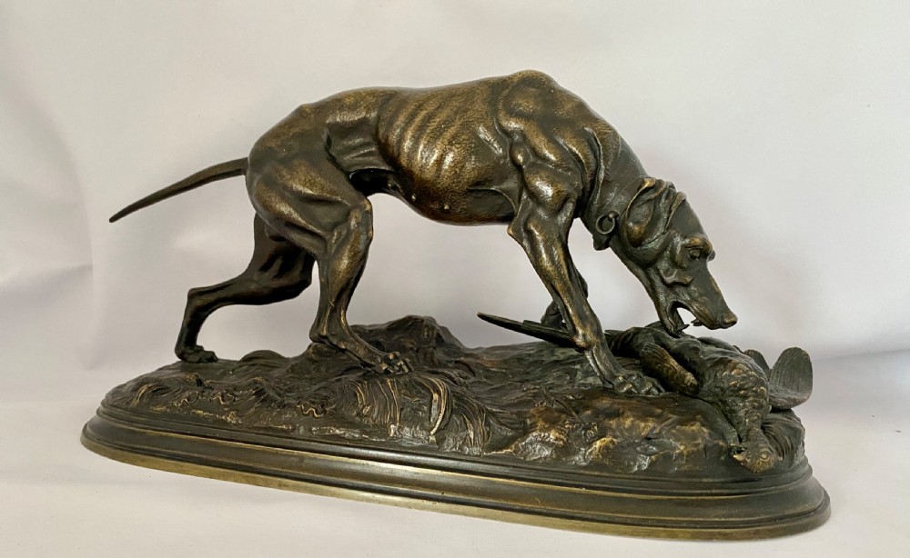 A nineteenth-century dark patinated bronze sculpture depicting a muscular gun dog retrieving a game bird on a moulded oval base.
