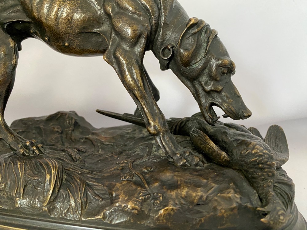A nineteenth-century dark patinated bronze sculpture depicting a muscular gun dog retrieving a game bird on a moulded oval base. View II