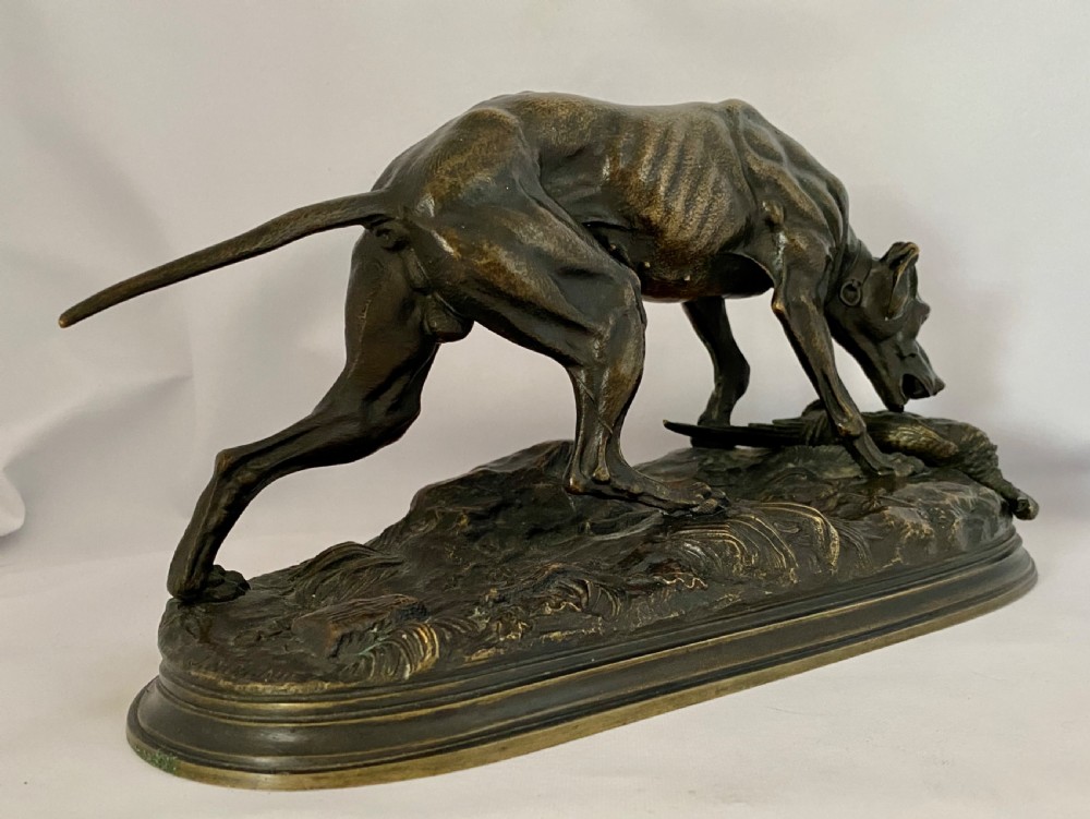 A nineteenth-century dark patinated bronze sculpture depicting a muscular gun dog retrieving a game bird on a moulded oval base. View III