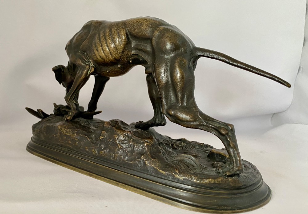 A nineteenth-century dark patinated bronze sculpture depicting a muscular gun dog retrieving a game bird on a moulded oval base. View IV
