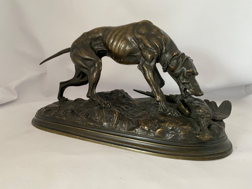 A nineteenth-century dark patinated bronze sculpture depicting a muscular gun dog retrieving a game bird on a moulded oval base. View VIII