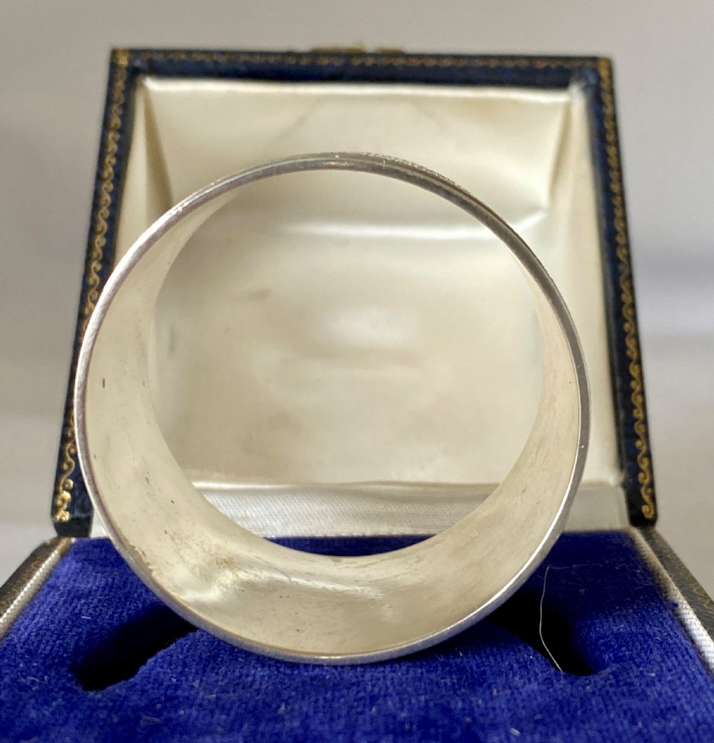 A cylindrical sterling silver napkin ring featuring a textured bark-effect surface, smooth polished borders, and visible stamped British hallmarks. View IV