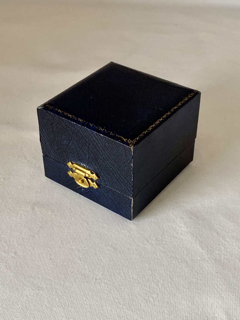A cylindrical sterling silver napkin ring featuring a textured bark-effect surface, smooth polished borders, and visible stamped British hallmarks. View VI