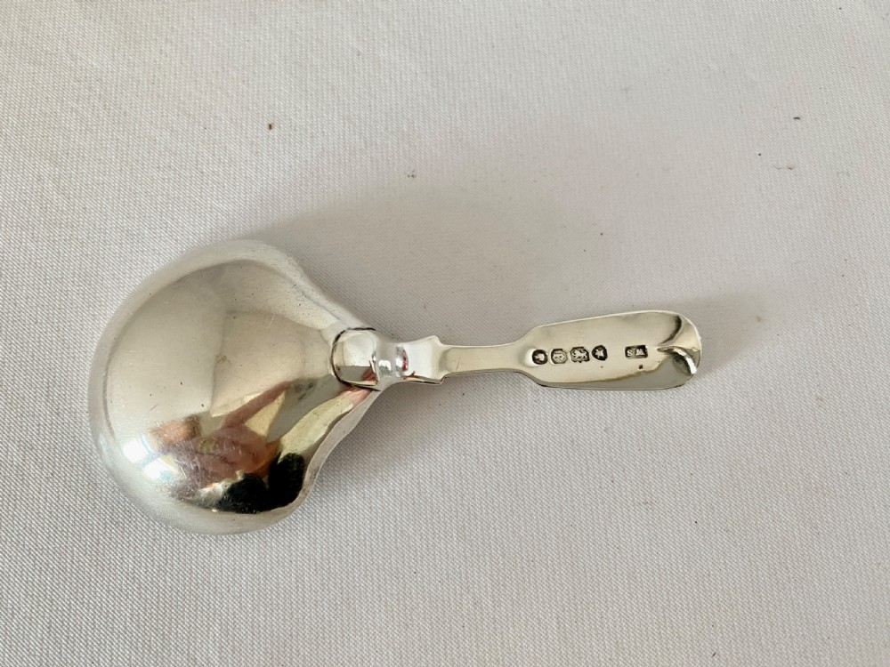 A Victorian sterling silver caddy spoon featuring a flared shovel-shaped bowl and a short handle engraved with a monogram. View III