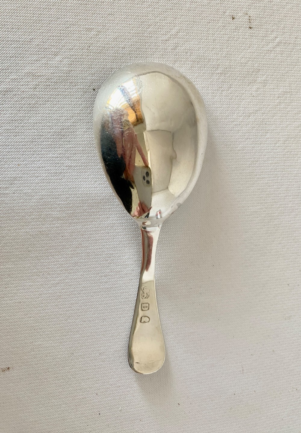 An antique sterling silver caddy spoon featuring an oval bowl with bright-cut engraved borders and a monogrammed handle. View V
