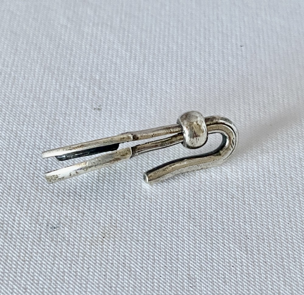 A solid sterling silver Victorian napkin clip featuring an engraved shield-shaped terminal and a sliding bar mechanism. View II