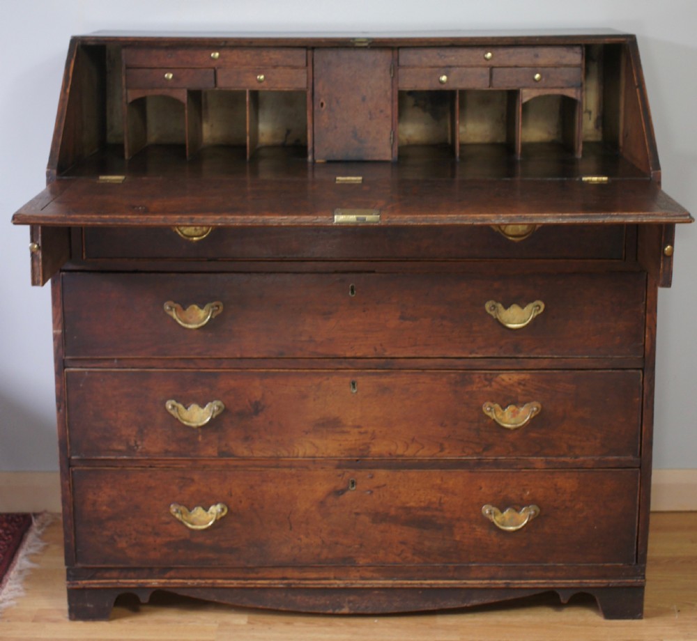 An 18th-century dark oak bureau featuring a slanted fall-front writing flap above four graduated drawers with brass handles. View II