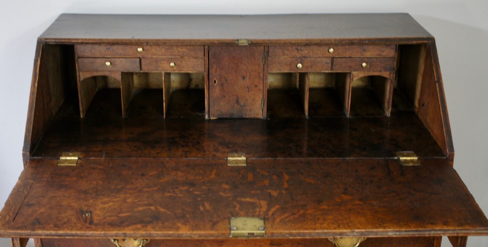 An 18th-century dark oak bureau featuring a slanted fall-front writing flap above four graduated drawers with brass handles. View III