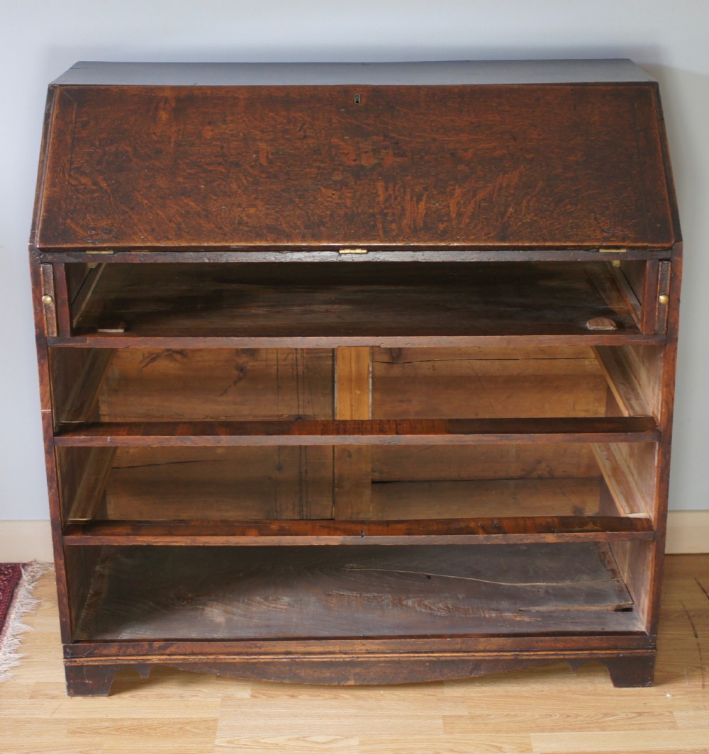 An 18th-century dark oak bureau featuring a slanted fall-front writing flap above four graduated drawers with brass handles. View VIII