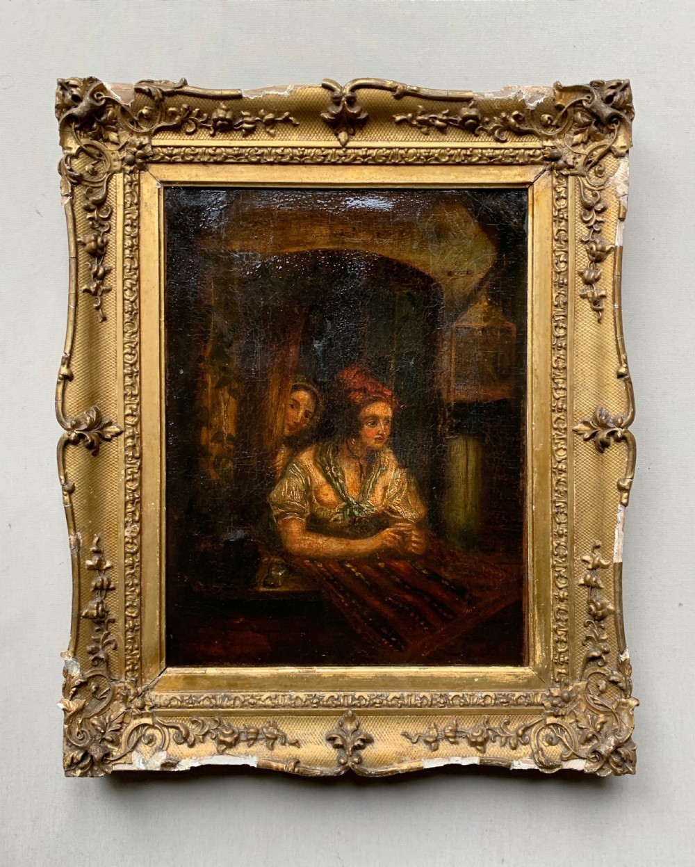 A 19th-century oil painting on canvas illustrating two figures in period dress within a dimly lit interior displaying craquelure throughout. View II