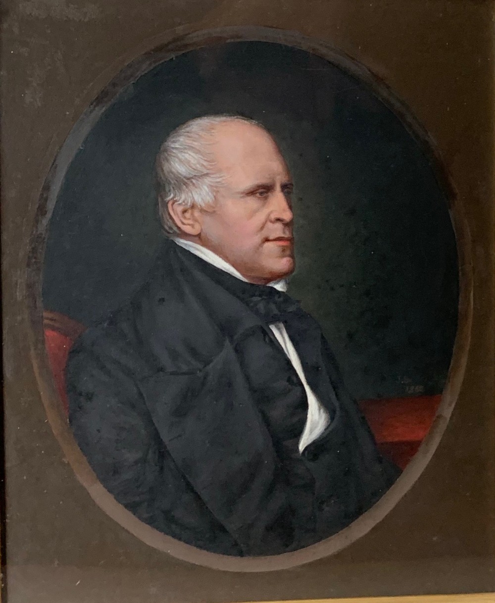 A nineteenth-century oil portrait depicting a gentleman with grey hair wearing a black formal coat set within an oval aperture.
