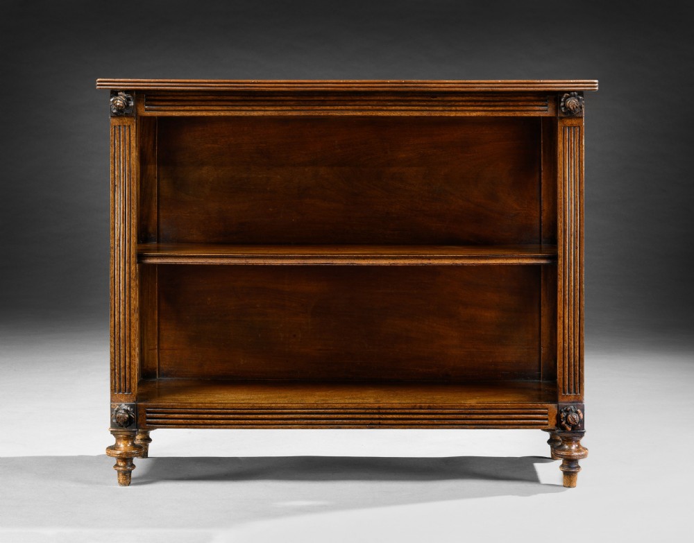A Regency mahogany open dwarf bookcase featuring two shelves, fluted side pilasters with carved rosettes, brass trellis side panels, and turned feet. View II