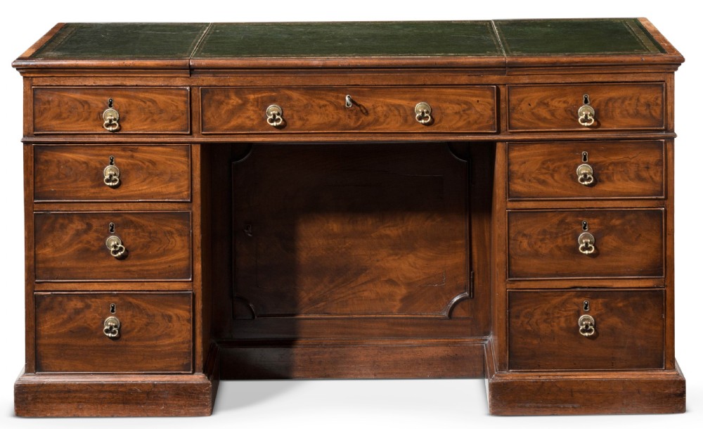 An 18th-century George III Chippendale mahogany pedestal desk featuring a green leather inset writing surface, flame mahogany drawer fronts, and brass drop handles.