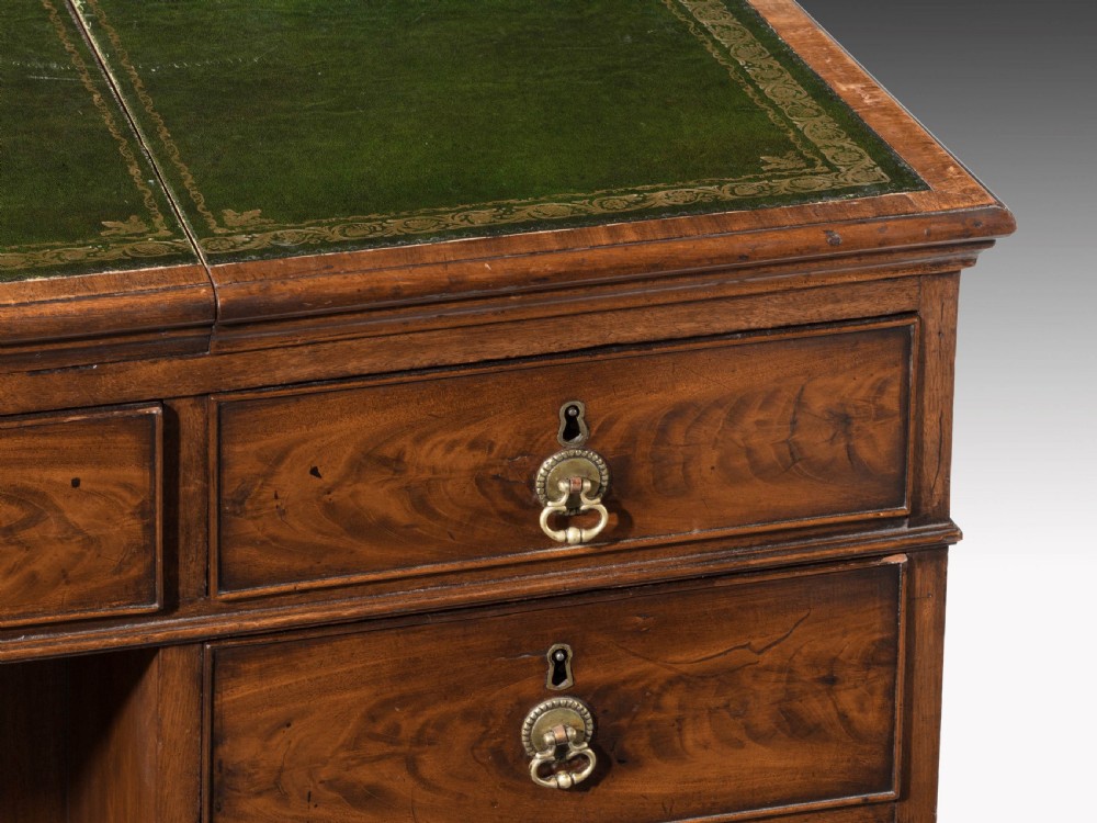 An 18th-century George III Chippendale mahogany pedestal desk featuring a green leather inset writing surface, flame mahogany drawer fronts, and brass drop handles. View III