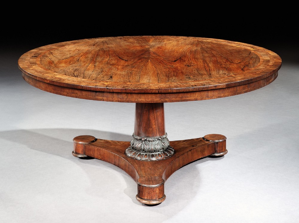 A circular antique rosewood centre table with book-matched grain and crossbanded border shown tilted upright on its base. View II
