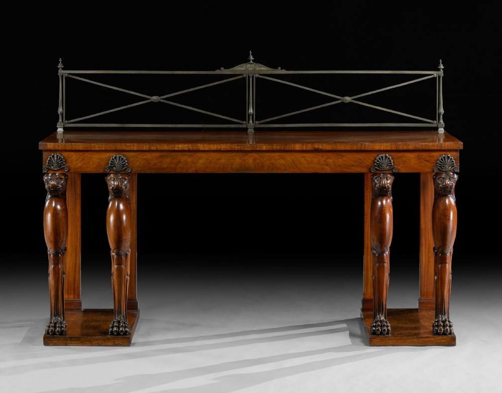 An Irish Regency mahogany serving table featuring four carved lion monopodium legs, dual plinth bases, and a brass gallery rail. View II
