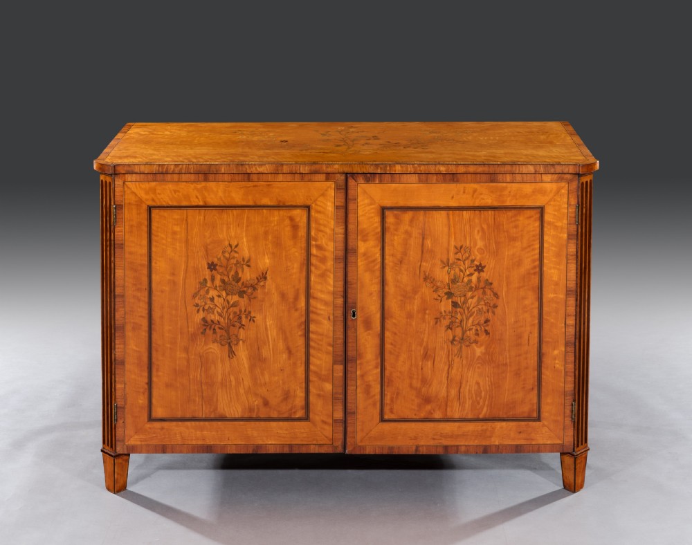 A late 18th-century George III satinwood cabinet featuring floral marquetry inlaid double doors, crossbanded borders, fluted pilasters, and square tapered feet.