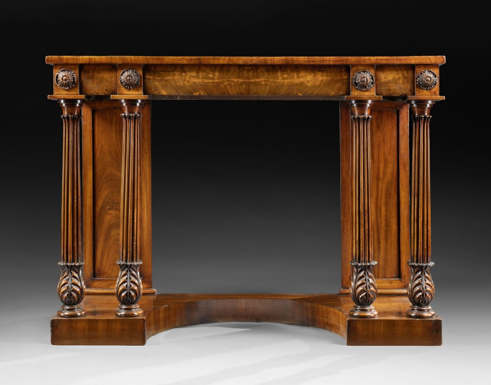 An antique George IV flame mahogany console table featuring twin fluted columns with carved acanthus leaf capitals, floral rosettes on the frieze, and a shaped plinth base. View II
