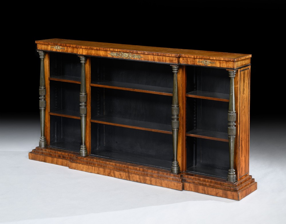 A low Regency breakfront open bookcase crafted from warm brown mahogany with turned columns and decorative brass mounts.
