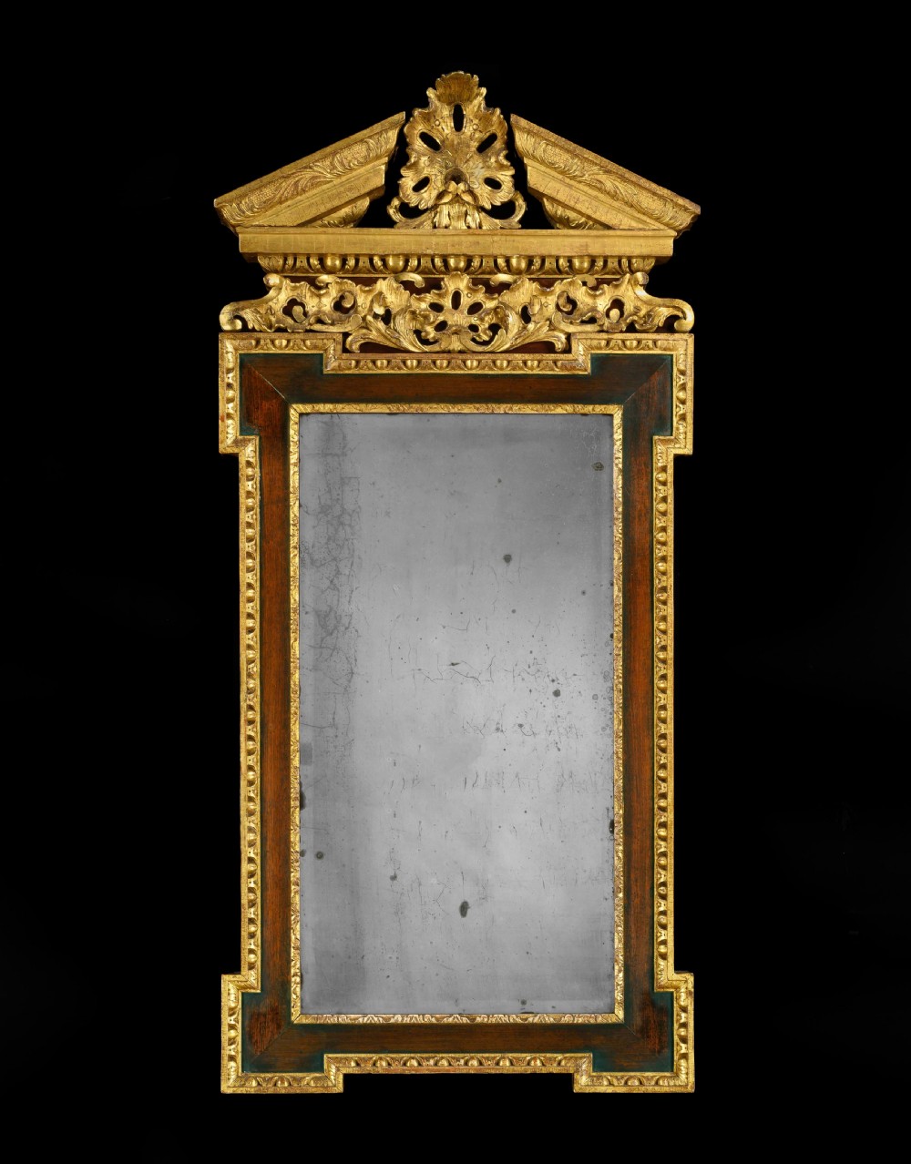 A George II Palladian wall mirror featuring a carved giltwood broken triangular pediment and dark wood crossbanded frame with an aged mirror plate.