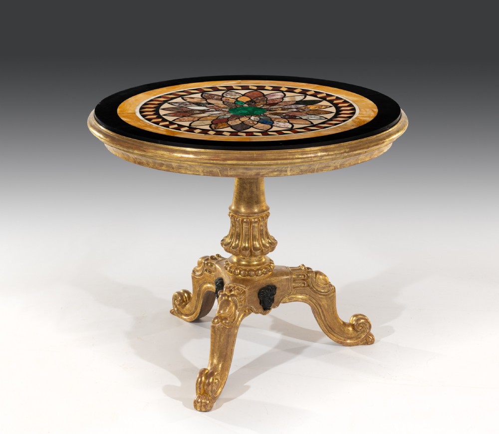 A circular William IV centre table featuring a floral specimen marble inlaid top supported on a fluted giltwood pedestal base with scroll legs.