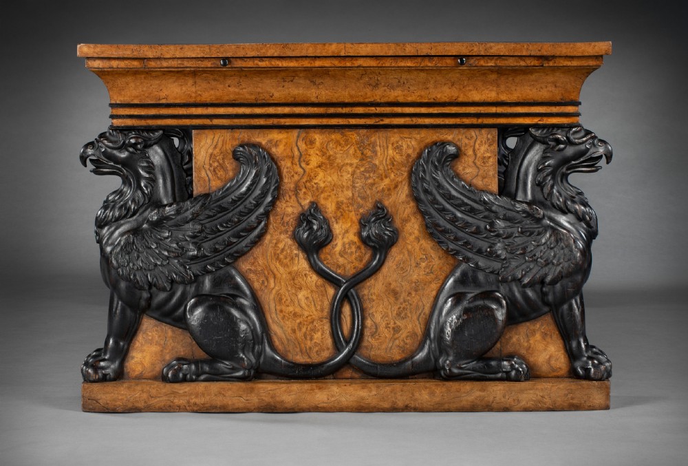 A Regency burr oak partners desk featuring a black leather writing top supported by carved ebonised winged griffins on plinth bases. View II