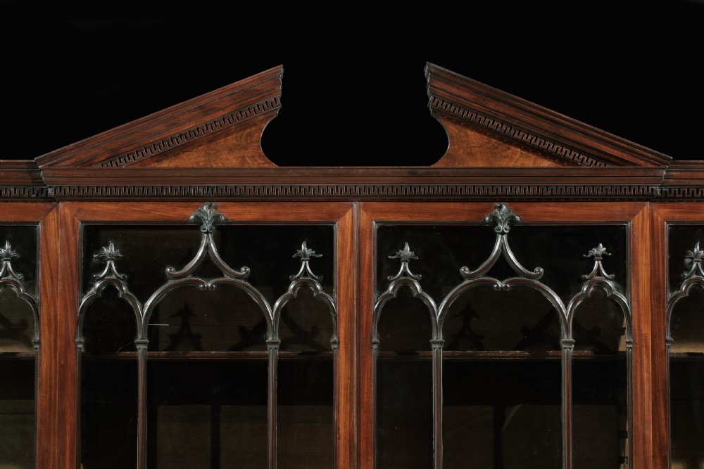 A large George III mahogany breakfront bookcase featuring a broken pediment, four Gothic astragal-glazed upper doors, and four solid mahogany cupboard doors below. View III