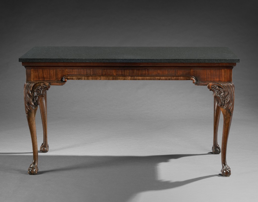 A George II mahogany side table featuring a dark rectangular stone top set above hand-carved cabriole legs with acanthus foliage knees.