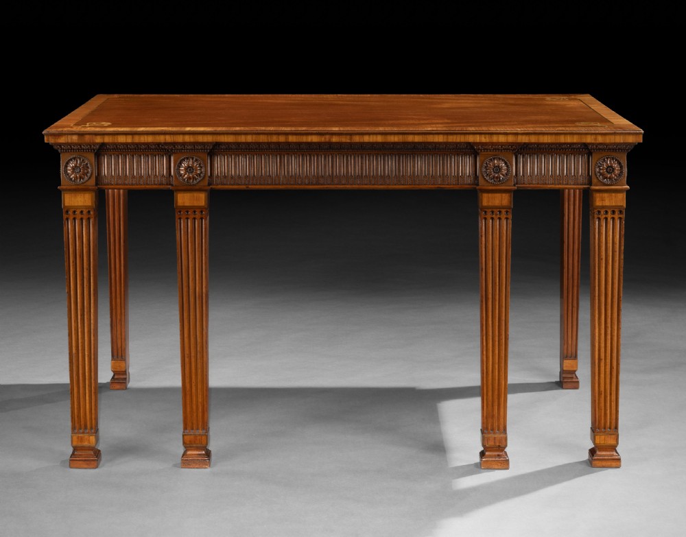 A rectangular George III mahogany console table featuring a fluted frieze, carved patera rosettes, corner inlay, and fluted square tapered legs.