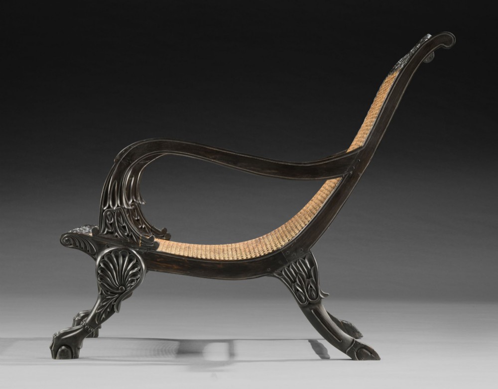 A pair of 19th-century Ceylonese carved ebony armchairs featuring woven cane seats and backrests, scrolled armrests, and carved paw feet. View II